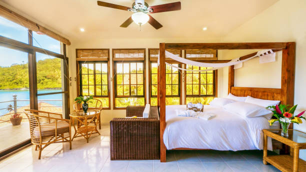 Beautiful tropical resort bedroom interior with comfortable furnishings and many windows looking out over island nature. Philippines. stock photo