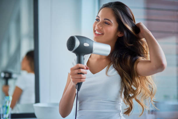 Putting great care into her hair Shot of an attractive young woman blowdrying her hair in the bathroom blow drying stock pictures, royalty-free photos & images