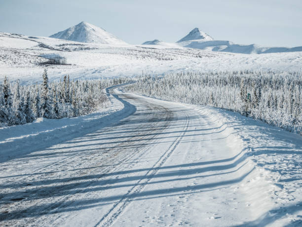 istock winding snowy road leading towards snow mountains 912872414