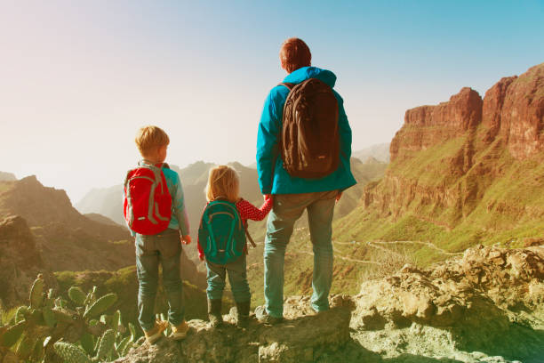 istock father and two kids hiking climbing in mountains 912872630