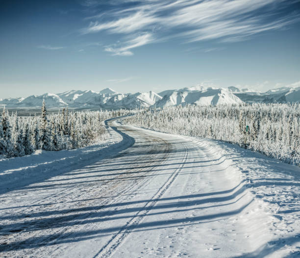 istock winding snowy road leading towards snow mountains 912872796
