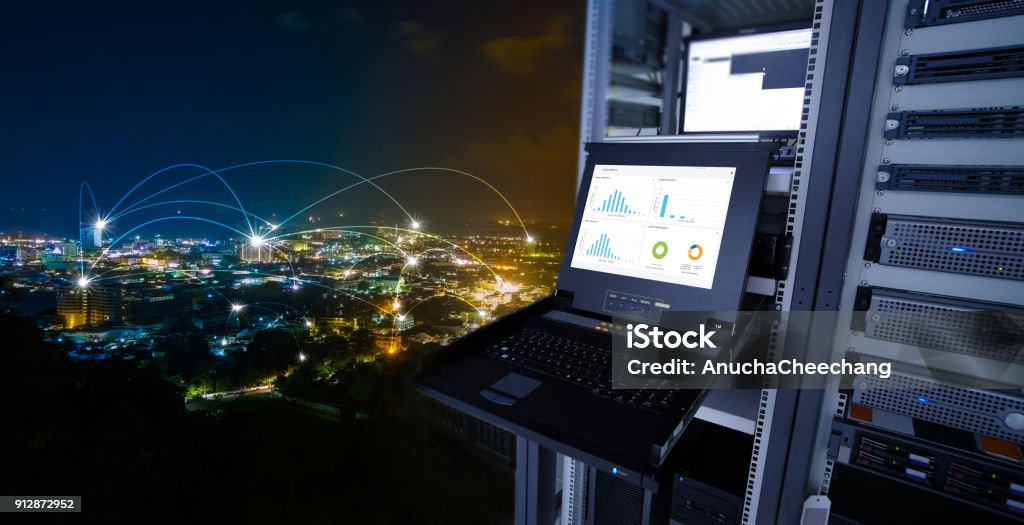 smart city concept. monitor show graph information of network traffic and status of device in the server room of the data center and blending with cityscape panorama of Phuket city, Thailand at night Network Server Stock Photo
