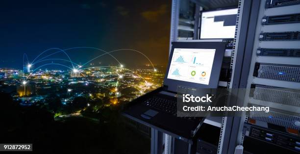 Smart City Concept Monitor Show Graph Information Of Network Traffic And Status Of Device In The Server Room Of The Data Center And Blending With Cityscape Panorama Of Phuket City Thailand At Night Stock Photo - Download Image Now