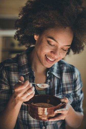 Young smiling black woman enjoying while eating cereals for her breakfast.