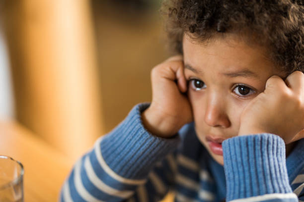 Close up of crying little black boy. Close up of sad African American boy with head in his hands. child sadness stock pictures, royalty-free photos & images