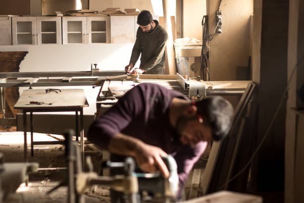 istock Carpentry workshop. Man using electric hand saw on wooden planks 912878752