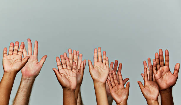 istock Many hands held aloft against gray background 912885664