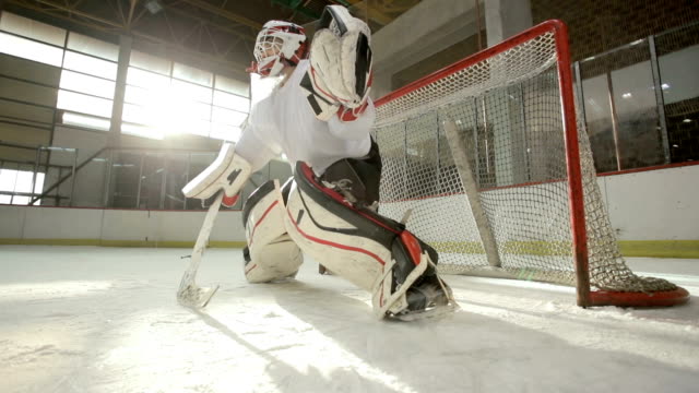 Slow motion of ice hockey goaltender failing to defend the goal in a rink.