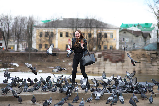 A girl on a walk in the park and a flock of pigeons
