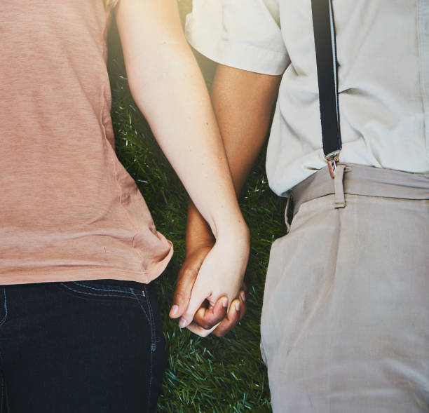 istock Cropped look at young couple lying on grass holding hands 912899974