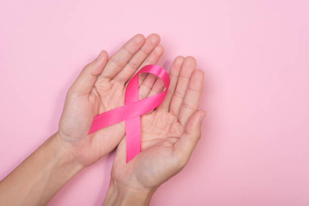 женщины стороны проведения розовая лента рака молочной железы на розовом фоне. с копировальной площадью - breast cancer pink ribbon alertness стоковые фото и изображения