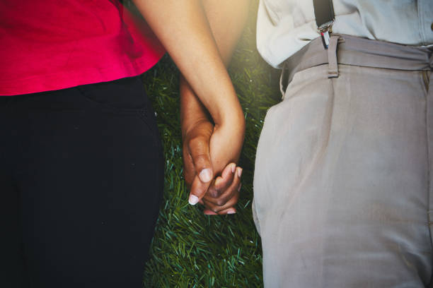 istock Cropped view of couple lying on grass holding hands 912903478