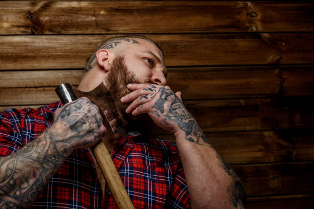 istock Tattooed man hang axe on wooden background. 912906784