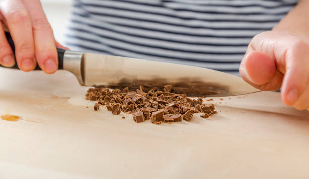 Cafe employee cuts the chocolate into small pieces. Woman prepares delicious, healthy cookies from spelt flour, oatmeal and chocolate stock photo
