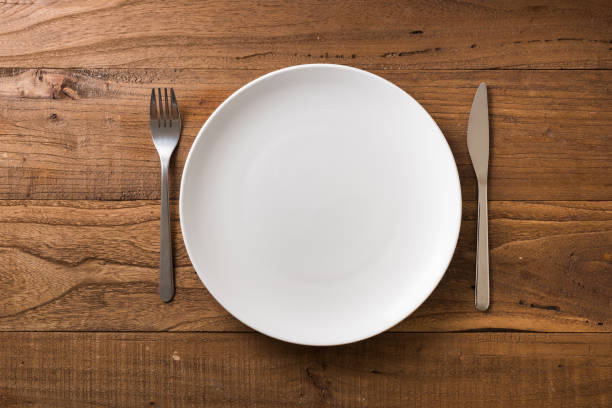 istock White Plate on brown wooden background with utensils 912910578