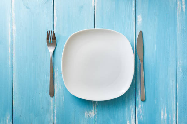 istock White Plate on blue wooden background with utensils 912911572