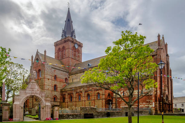 el st magnus cathedral, fundada en 1137, domina el horizonte de kirkwall, la ciudad principal de las islas orkney, escocia. - uk cathedral cemetery day fotografías e imágenes de stock