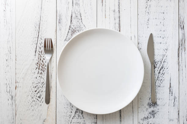 istock Plate on white wooden background with utensils 912913602