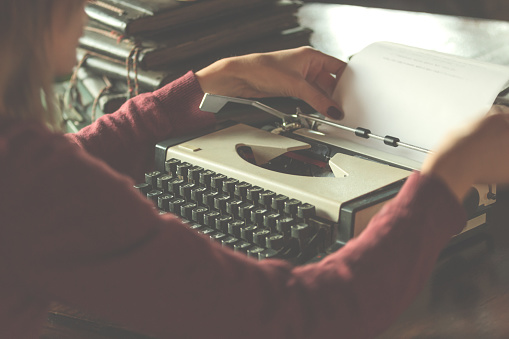 Woman writing on the vintage typing-machine. Shallow depth of field on keyboards.