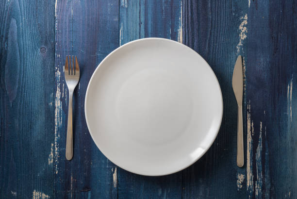 istock White Plate on blue wooden background with utensils 912915112