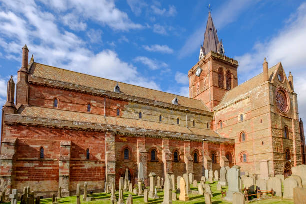 el st magnus cathedral, fundada en 1137, domina el horizonte de kirkwall, la ciudad principal de las islas orkney, escocia. - uk cathedral cemetery day fotografías e imágenes de stock