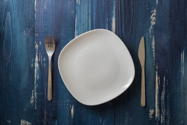 istock White Plate on blue wooden background with utensils 912918964