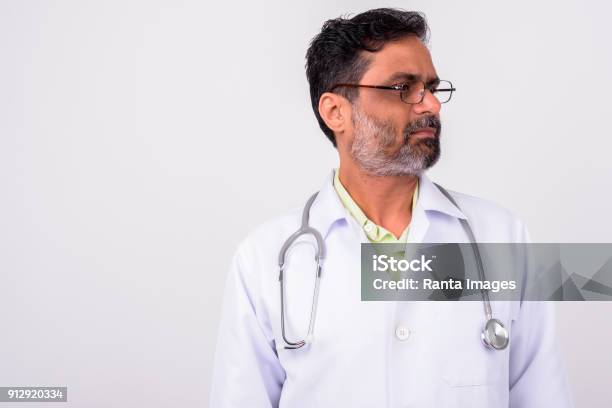 Indian Man Doctor Against White Background Stock Photo - Download Image Now - Looking Away, Portrait, Mature Men