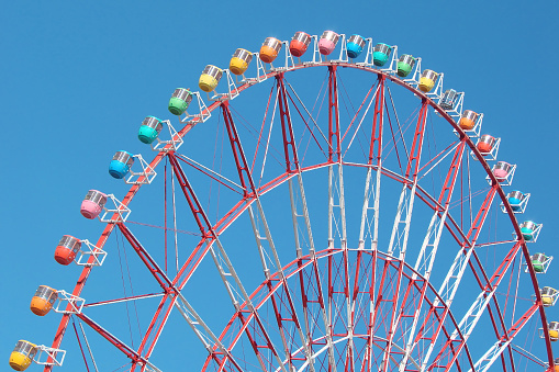 Colorful cabins on a Ferris wheel, blue sky background