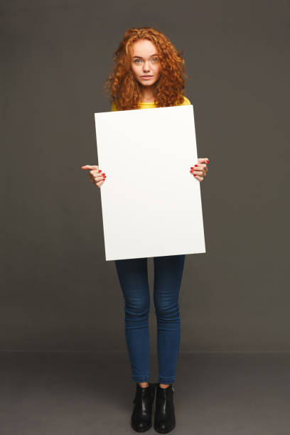 istock Young happy woman with blank white paper 912927774