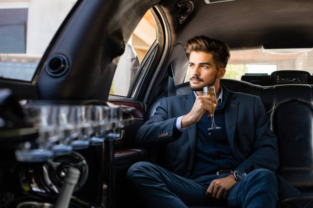 Business man in limousine with glass of champagne Business man in limousine with glass of champagne, enjoying status car photos stock pictures, royalty-free photos & images