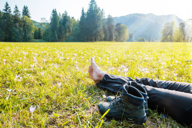 Traveler resting on a mountain plateau. POV view, legs close up on the background of mountain landscape