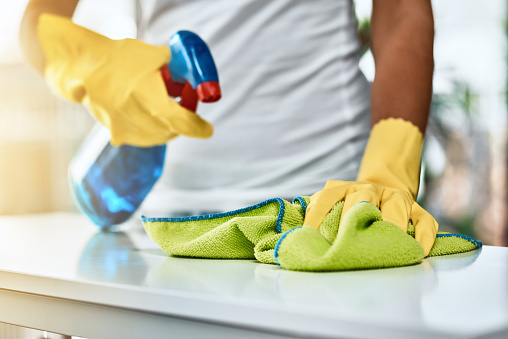 Shot of an unrecognizable woman cleaning a table at home