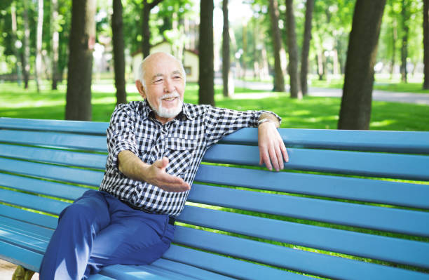 istock Smiling senior man sitting on the bench in park 912933382