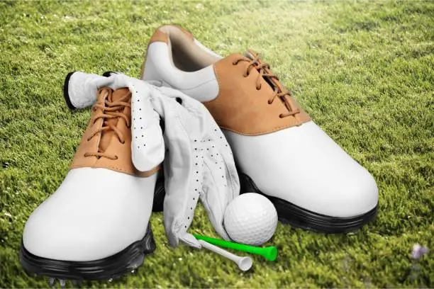 Pair of golfing shoes  on green grass background
