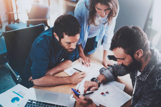 istock Teamwork working process.Group of young coworkers working together in modern office loft.Man using mobile phone.Blurred background.Horizontal. 912972206