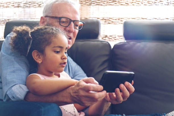 istock Grandfather playing with granddaughter on a mobile 912979278