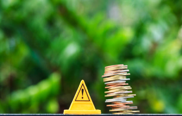 istock Financial risk. Coins falling and Warning label on nature background 912992874
