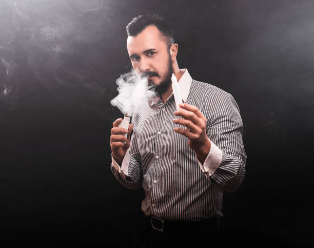 istock Man smokes electronic cigarette. Smoking and vaping on black 913001704