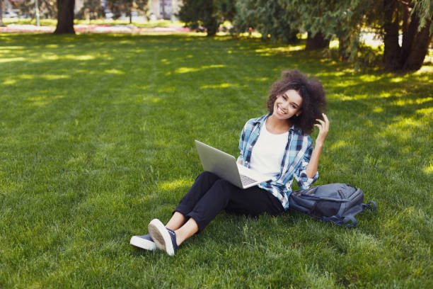 istock Cheerful young woman using laptop in park 913003886