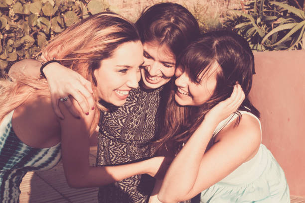 trois jeunes femmes s’étreignent dans une journée ensoleillée. - retro revival outdoors close up europe photos et images de collection