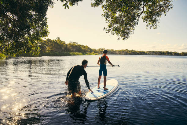 mijn jongen onderwijzen hoe te peddelen - paddle surfing stockfoto's en -beelden