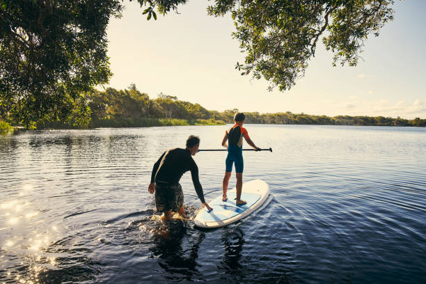 Teaching my boy how to paddle Shot of a father and son enjoying a day outdoors standing water photos stock pictures, royalty-free photos & images