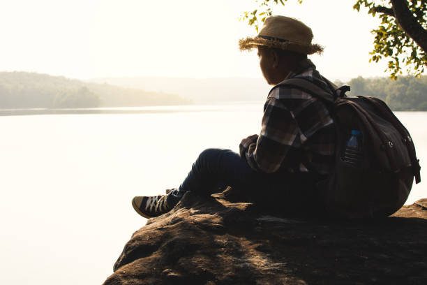 istock Side View Of Boy Sitting On Rock Against Sea 913049260