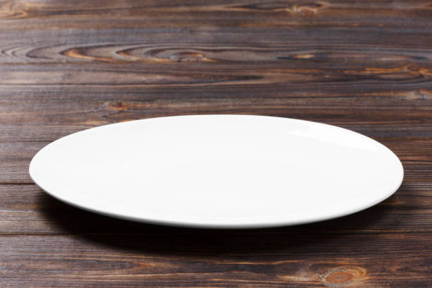 istock white plate on the wooden brown table. Perspective view 913055618
