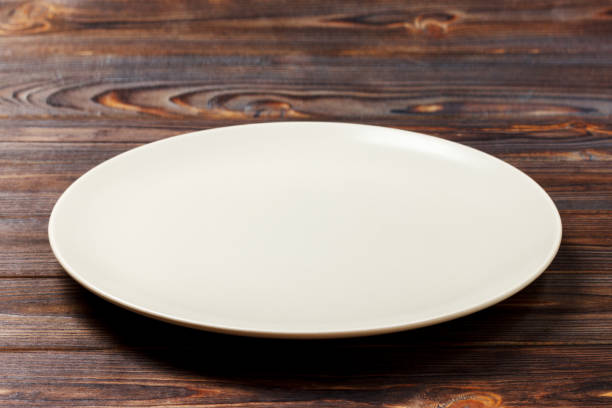istock empty round plate for food on wood bachground. Perspective view 913055620