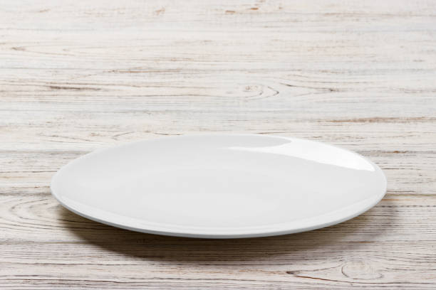 白い木製テーブルの背景に白の丸皿。分�析観点ビュー - plate blue dishware white ストックフォトと画像