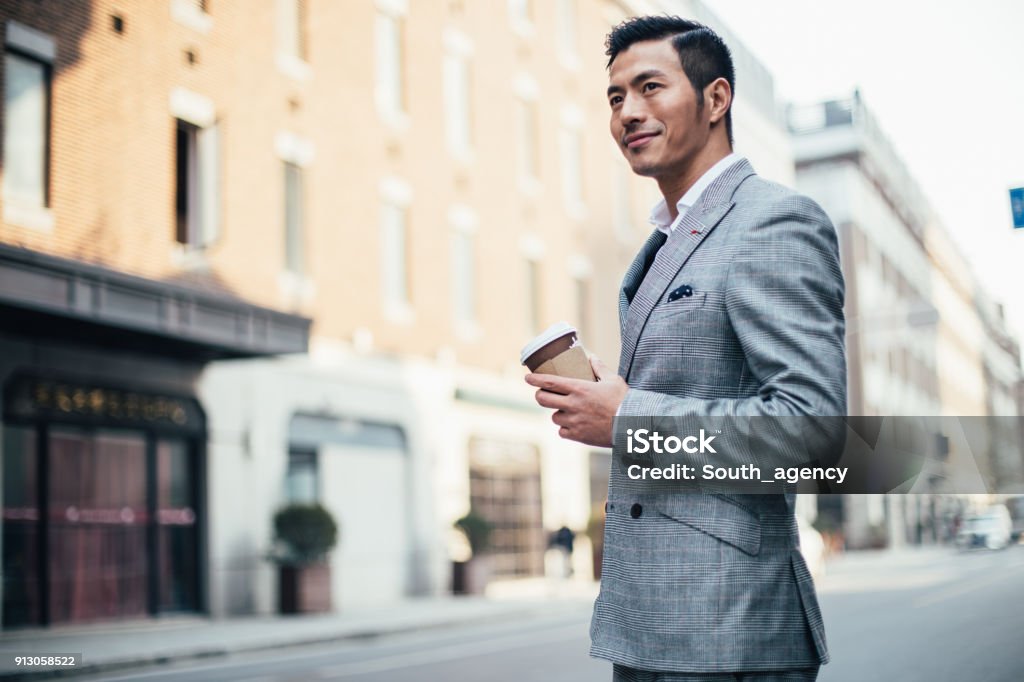 Coffee to go One man, standing on the street downtown, holding a cup of coffee. Businessman Stock Photo