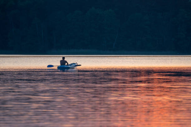 istock Summer relaxing activity. Young man kayaking on the lake. Sunset 913058774