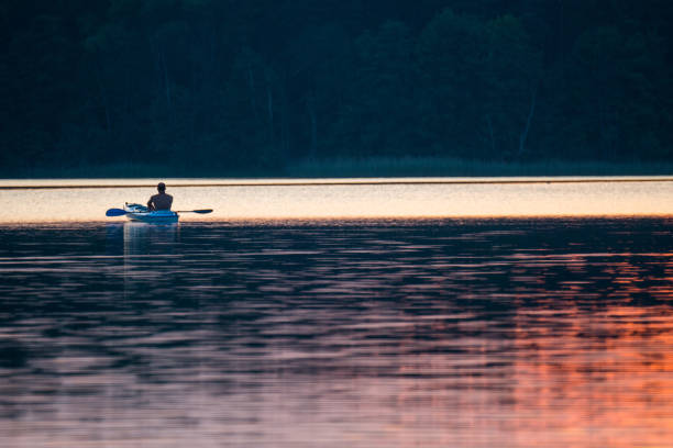 istock Summer relaxing activity. Young man kayaking on the lake. Sunset 913058808