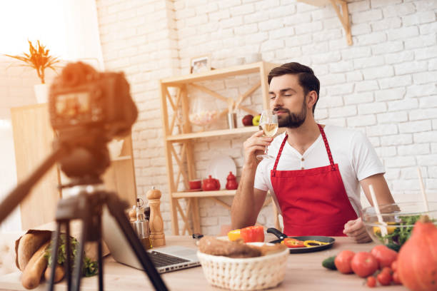 istock Chef tasting wine for culinary podcast shooting. Vegetables and kitchen utensils. 913066114
